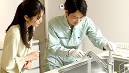 水道のトラブルをチェックする業者の男性と主婦